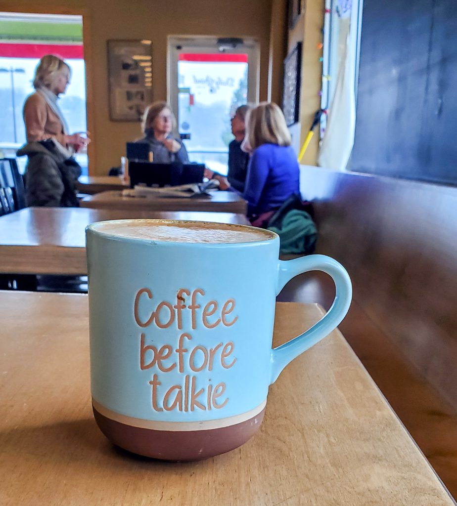 Coffee before talkie mug of coffee with customers in background at The Daily Grind in Stillwater Minnesota